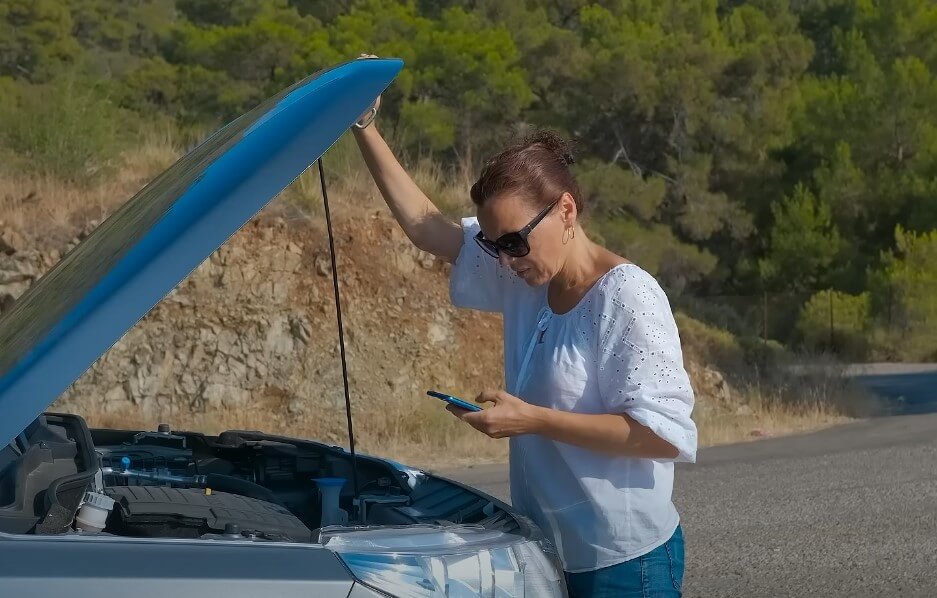 Žena podiže haubu automobila, proverava izvor kvara